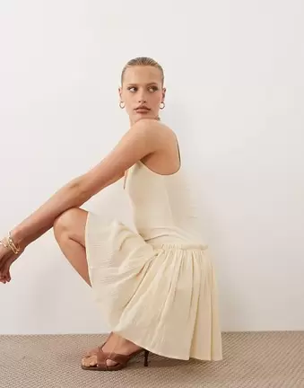 ASOS DESIGN – Baumwoll-Minikleid in Buttermilchgelb mit tief angesetzter Taille und Rockteil mit Knitterstruktur